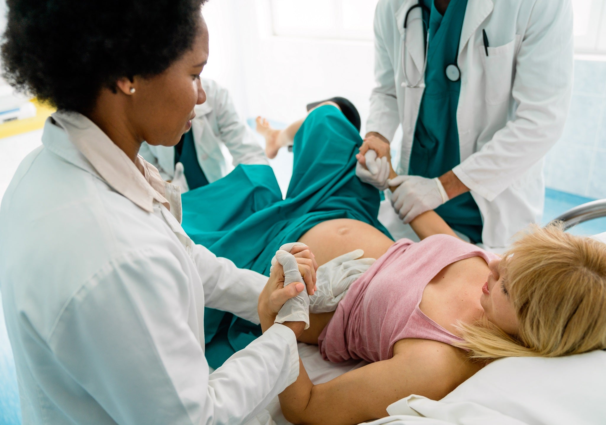Medica segurando mão da mãe gravida durante o parto
