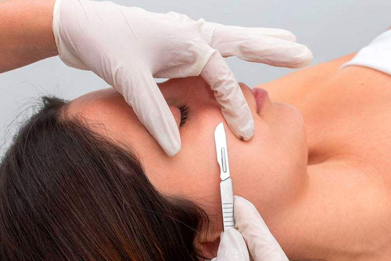 Esthetician treating a  woman's skin face with dermaplaning procedure